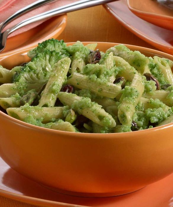 Prendete 400 g di broccoletti, puliteli, divideteli in cimette e lessateli, preferibilmente al vapore, per 10-15 minuti. Fate tostare 60 g di pistacchi sgusciati in un padellino antiaderente per circa un minuto, mescolando. Frullate i pistacchi con uno spicchio d'aglio sbucciato, 4 cucchiai di parmigiano grattugiato e una presa di sale, unendo a filo 6 cucchiai di olio EVO, fino a ottenere una crema. Frullate a parte i broccoletti, trasferite la purea ottenuta in un tegame antiaderente e fatela asciugare a fiamma vivace. Unite la crema di pistacchi e mescolate. Cuocete 400 g di penne al dente in una casseruola con abbondante acqua bollente salata, scolatele con cura, conditele in una terrina con la crema di broccoletti e pistacchi preparata, mescolate bene e servite.